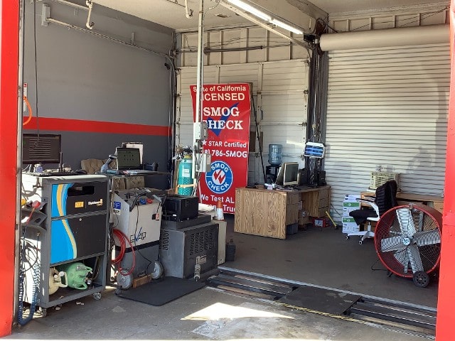 A garage filled with various smog testing equipment and a sign