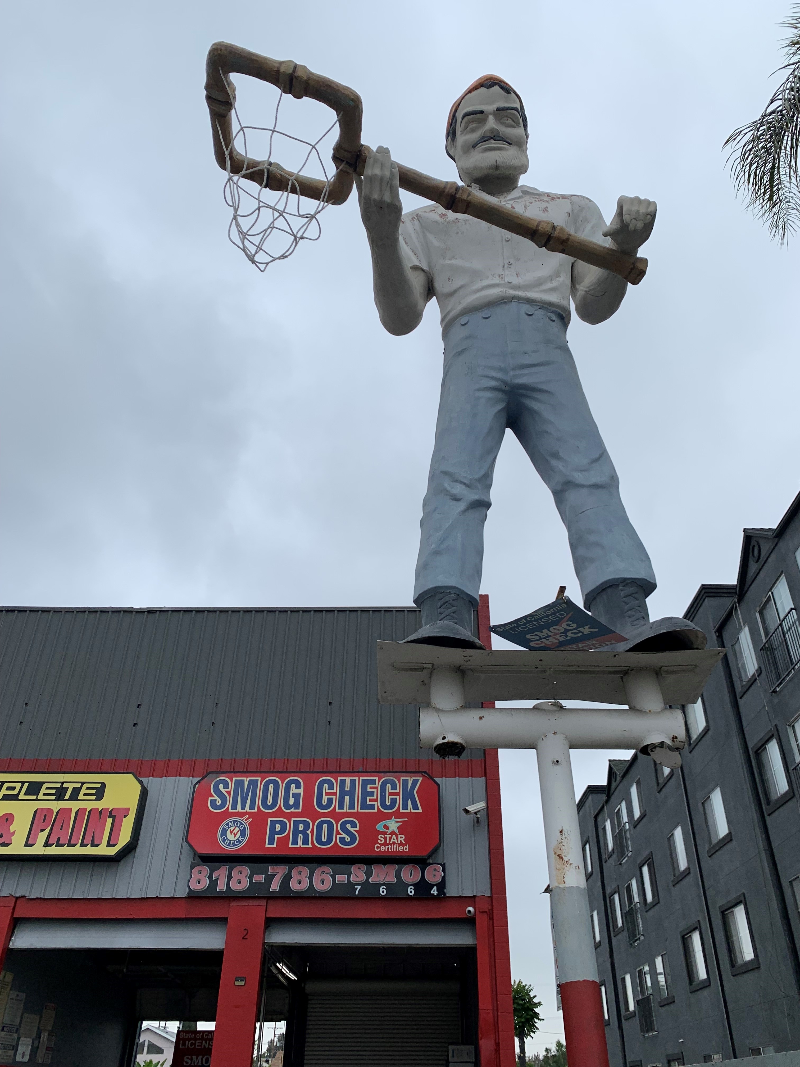 A statue of a man holding a net; off of Sherman Way, east of Sepulveda Blvd