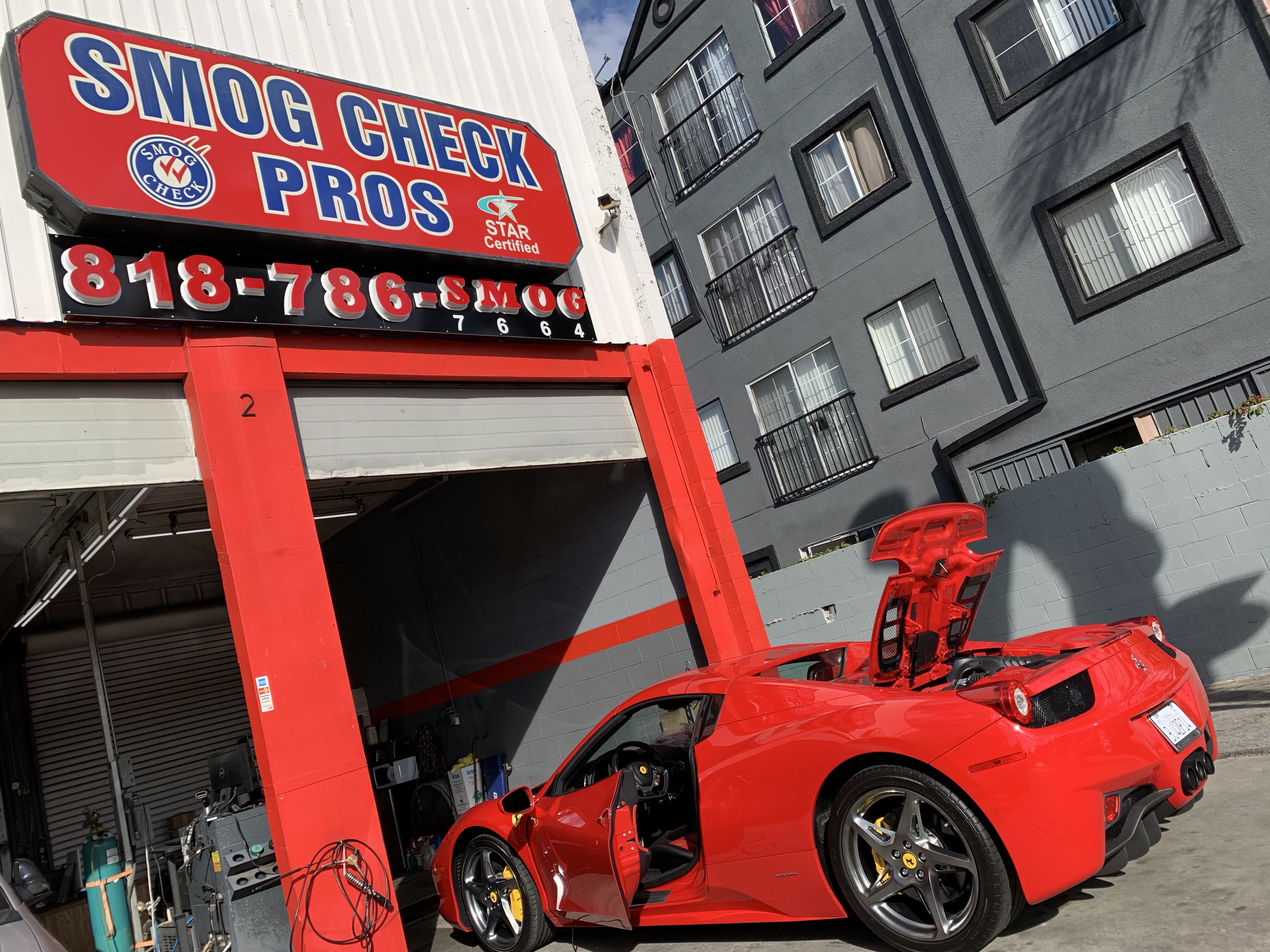 A red sports car being smogged in front of a garage