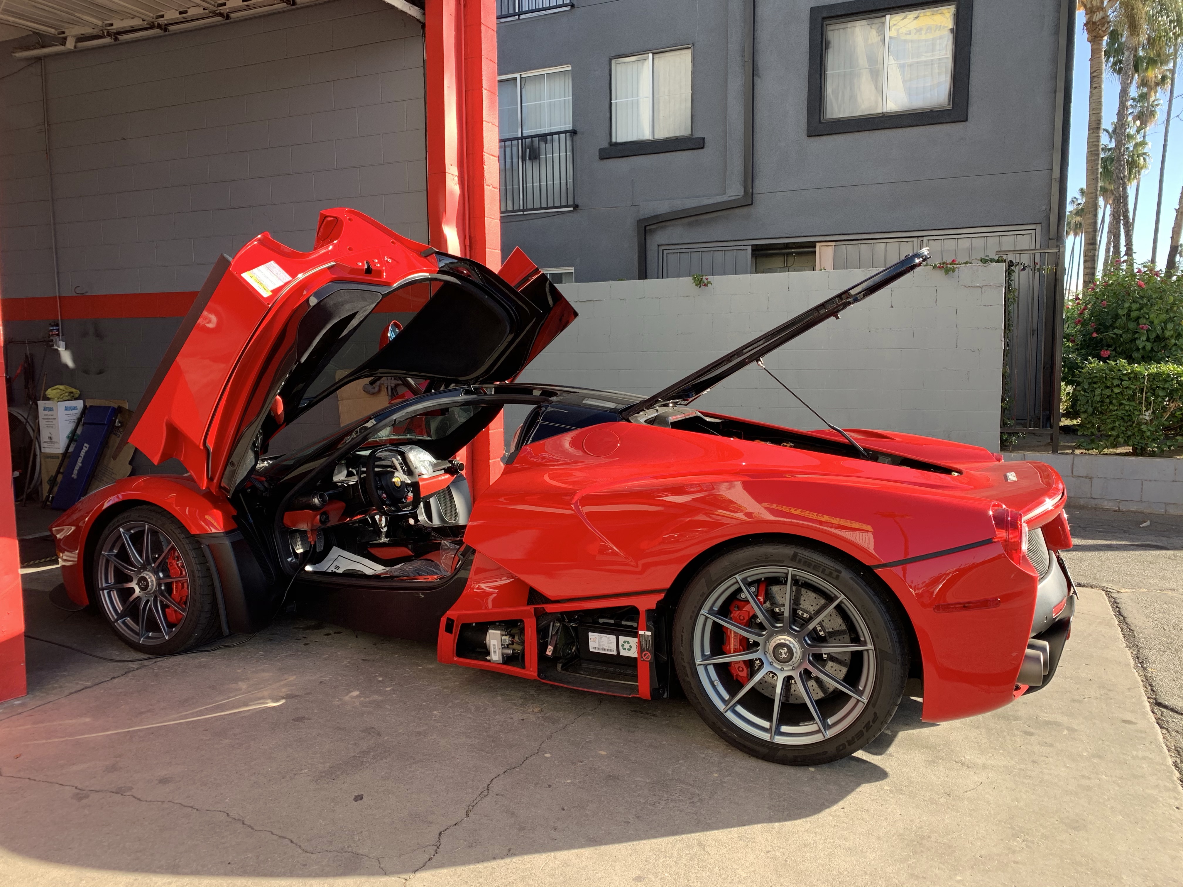 Smog testing in progress on a red sports car with its hood open